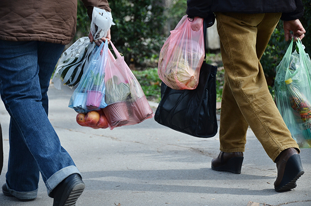 People walking carrying plastic bags full of groceries