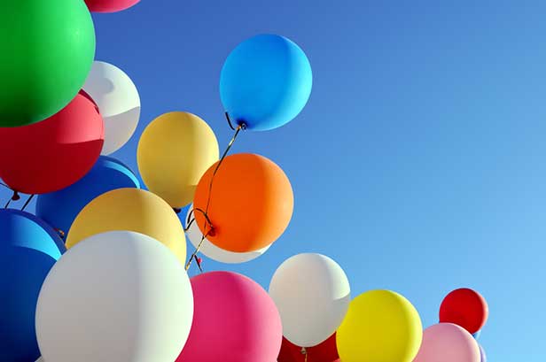 Colorful balloons rising towards blue sky