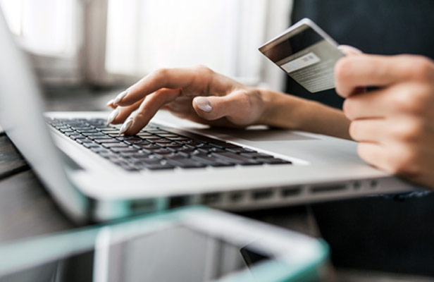 woman typing credit card info onto laptop