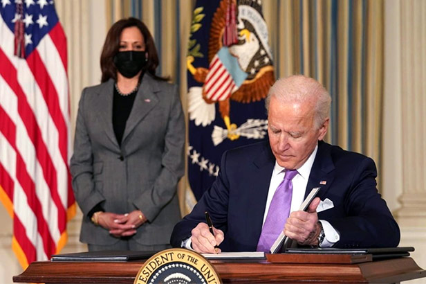 Kamala Harris watching while Joe Biden signs bill