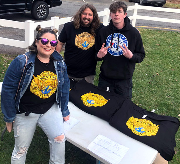 Woman and two men outside selling Wrestlemania t-shirts