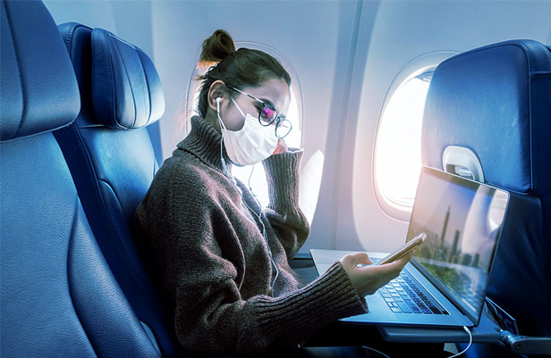 Woman on plane wearing mask and texting