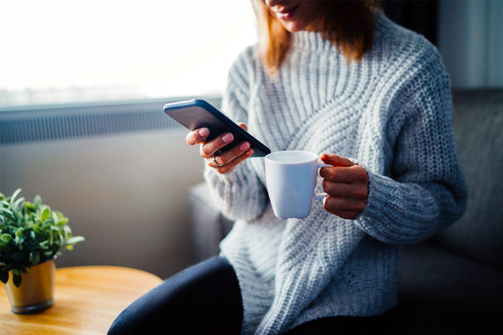 woman drinking coffee and looking at phone