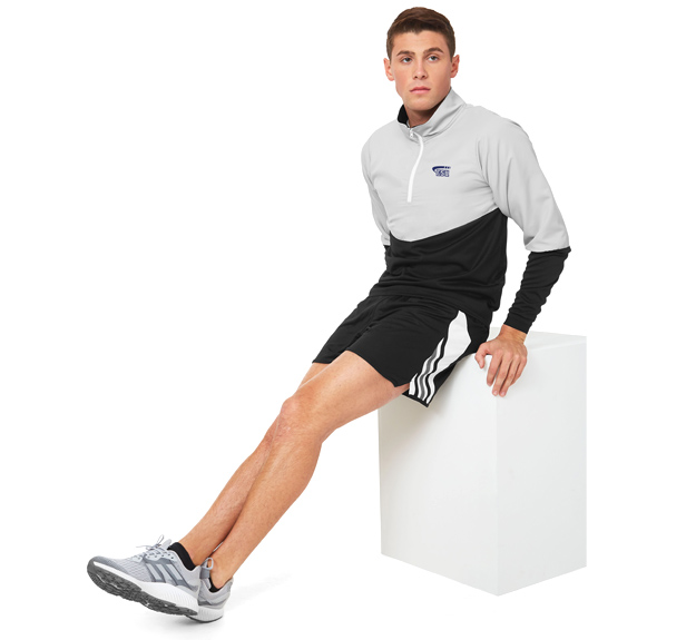 man sitting on box wearing shorts and quarter-zip pullover