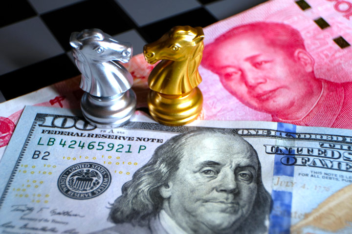Chinese and U.S. money underneath silver and gold chess pieces