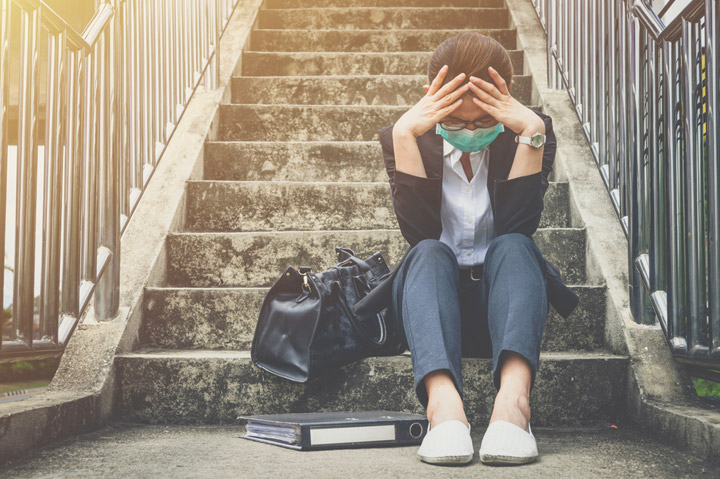 Stressed woman sitting on steps with head in hands