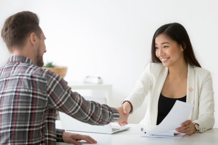 woman hiring manager shaking hands with male prospective employee