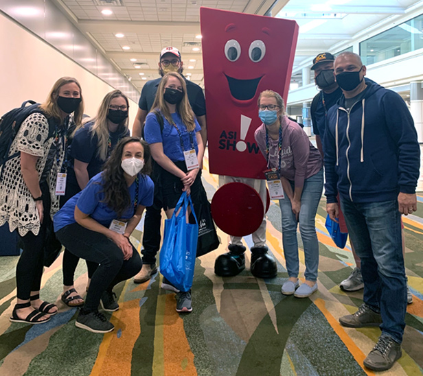 Liquid Screen employees standing next to Promo at ASI show