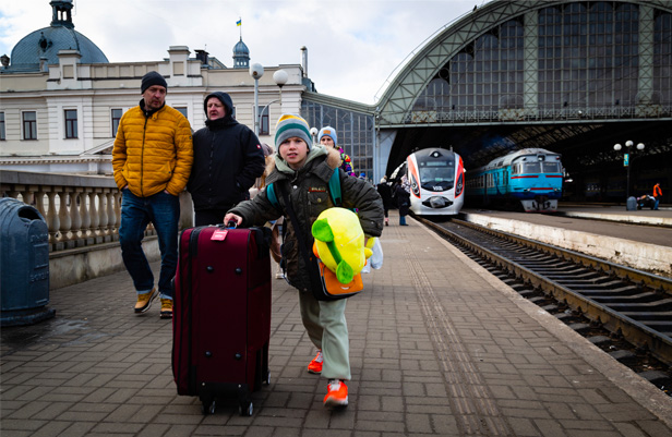 young Ukrainian refugee rolling luggage at train station