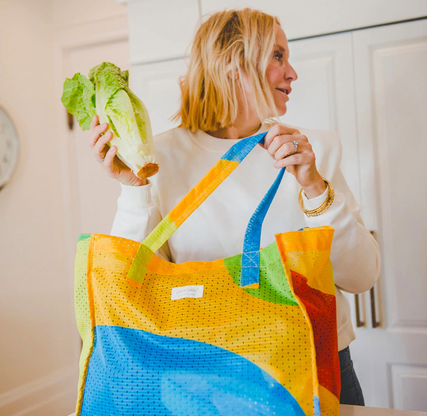 blond woman holding multi-color reusable shopping tote