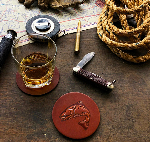 leather coaster, pocket knife, whiskey in glass on desk