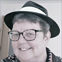 Ellen Overcast smiling, wearing patterned shirt and black hat and glasses