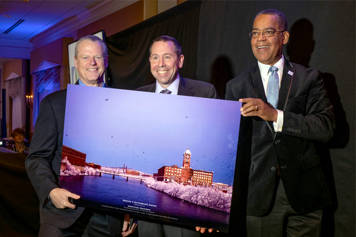 three men holding up a large photo