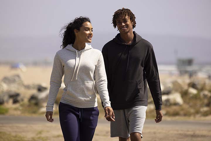 Young people walking on beach in Next Level Apparel clothing