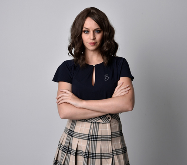 woman wearing plaid skirt, arms folded across chest