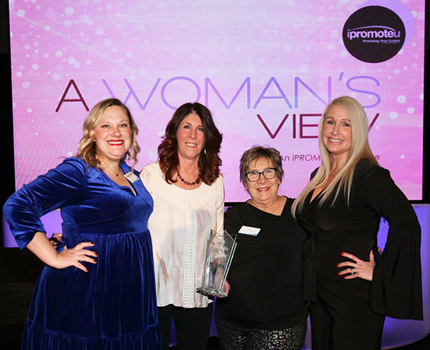 four women standing together with crystal award