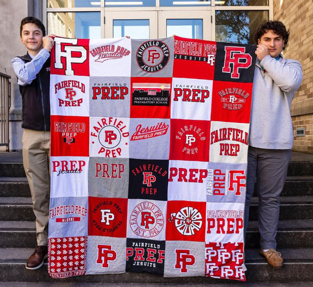 two young men holding up quilt