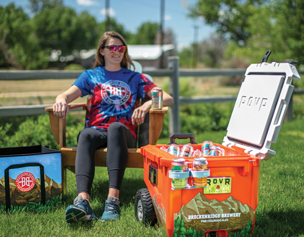 woman sitting next to large cooler full of beverages