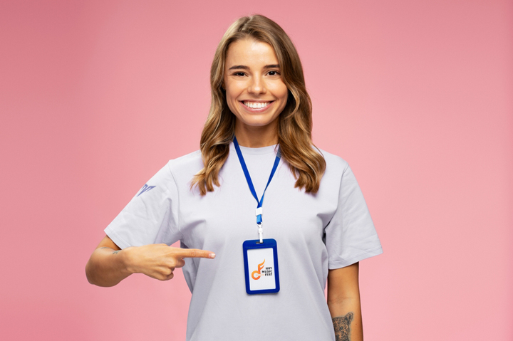 smiling woman pointing to lanyard hanging around her neck