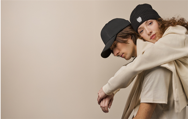 woman hugging man from behind, both wearing hats