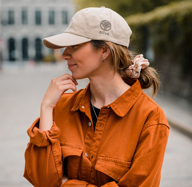 woman wearing orange shirt, cap, smiling